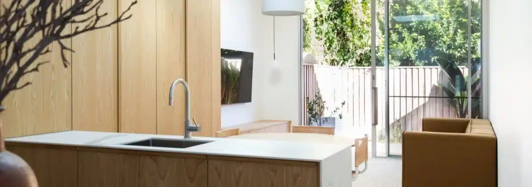 Modern kitchen and living area with natural light and timber cabinetry